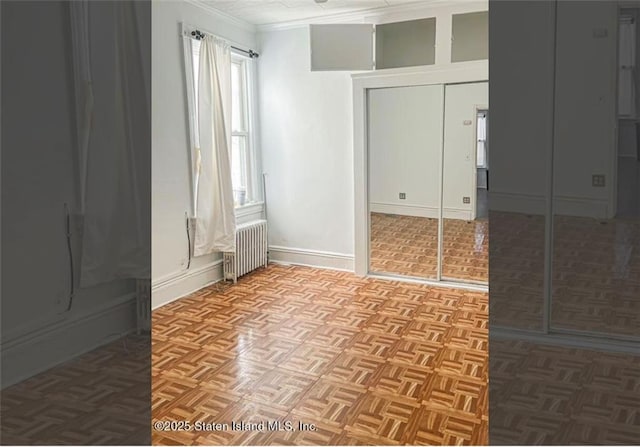 unfurnished room with radiator, ornamental molding, and light parquet flooring