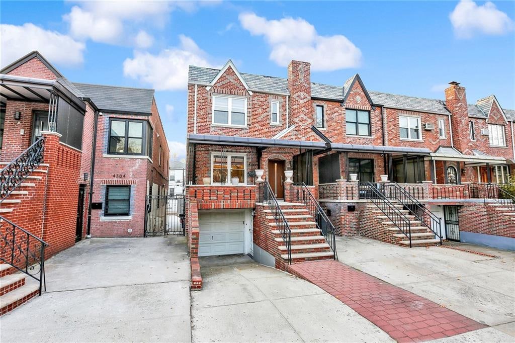 townhome / multi-family property featuring a garage, stairs, concrete driveway, and brick siding