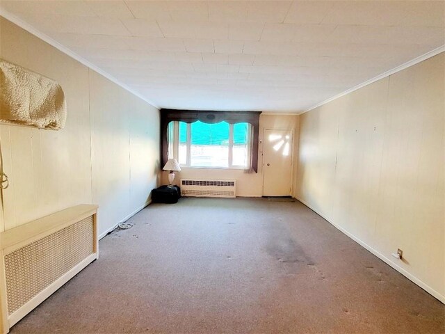 carpeted spare room with radiator heating unit and crown molding