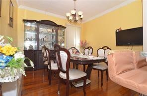 dining room featuring crown molding, an inviting chandelier, and wood finished floors