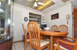 dining space featuring a ceiling fan, a paneled ceiling, and tile patterned floors