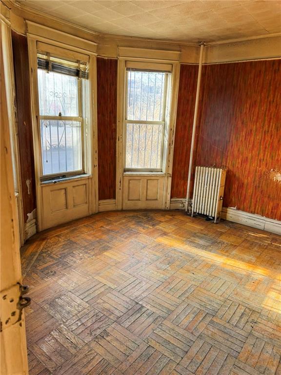 unfurnished room with radiator and parquet floors