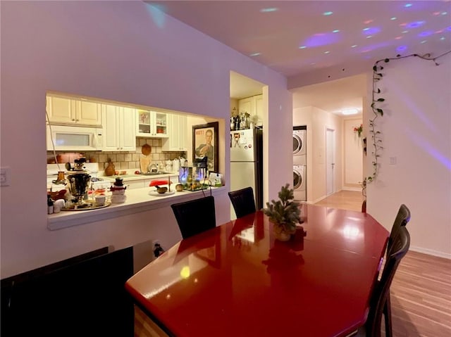 dining area with stacked washer and clothes dryer and light hardwood / wood-style floors