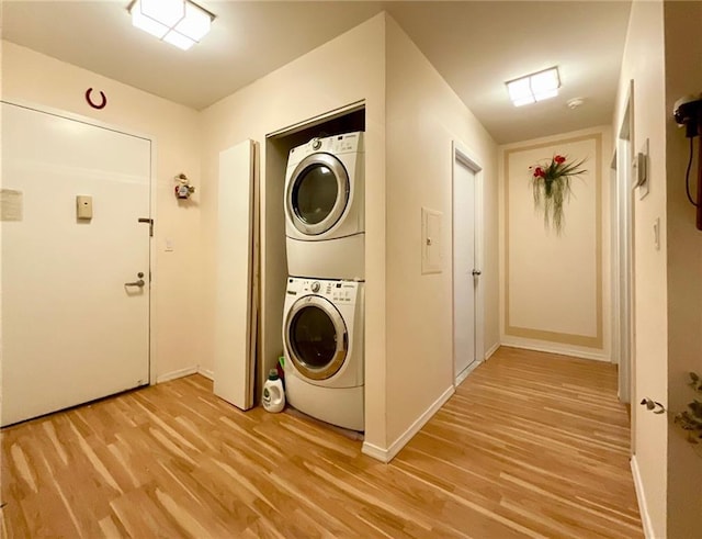 clothes washing area featuring stacked washer and dryer and light hardwood / wood-style flooring