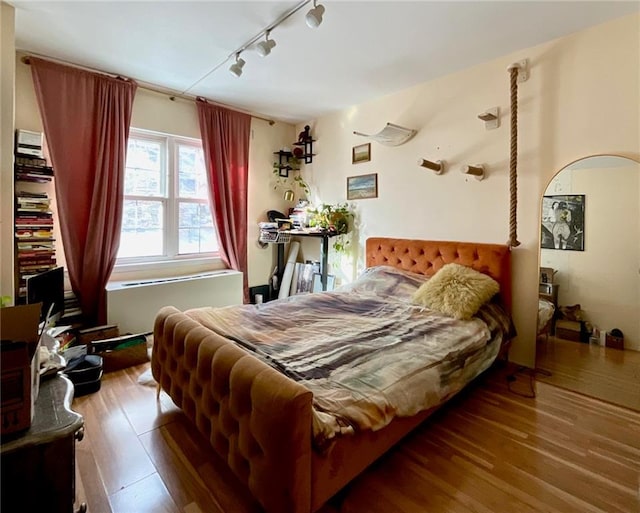 bedroom with rail lighting and hardwood / wood-style flooring