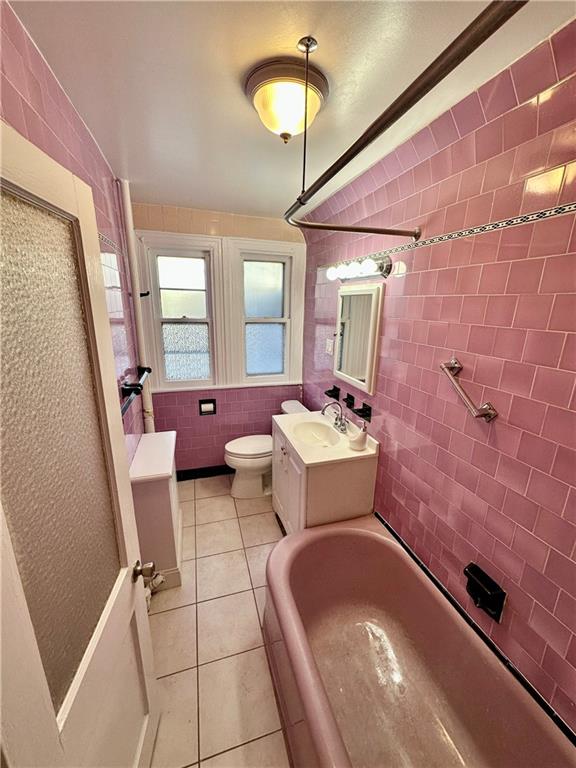 full bathroom featuring toilet, tile patterned flooring, vanity, washtub / shower combination, and tile walls