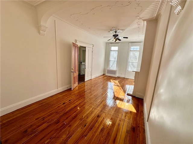 empty room featuring ceiling fan, ornamental molding, hardwood / wood-style floors, and baseboards