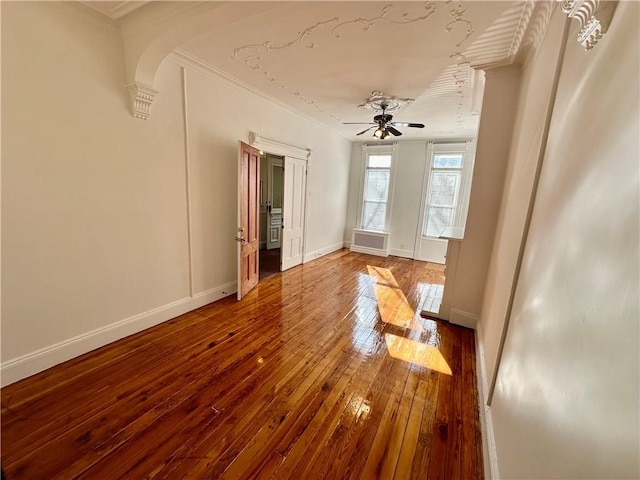 13 Windsor Pl, Brooklyn, NY 11215 - empty room with crown molding, wood-type flooring, a ceiling fan, baseboards, and arched walkways