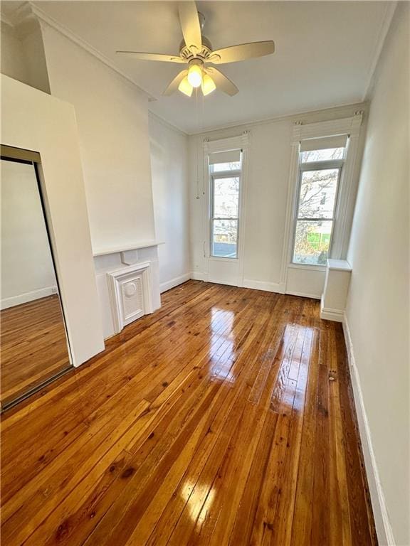 unfurnished living room featuring ornamental molding, ceiling fan, baseboards, and hardwood / wood-style flooring