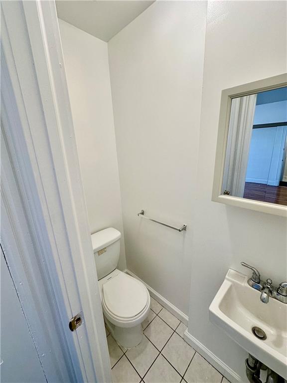 bathroom with toilet, tile patterned flooring, and sink