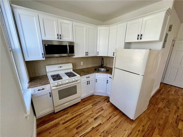 kitchen featuring white cabinetry, sink, white appliances, and light hardwood / wood-style flooring