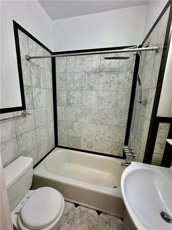 bathroom featuring toilet, tile patterned floors, a sink, and shower / bathtub combination