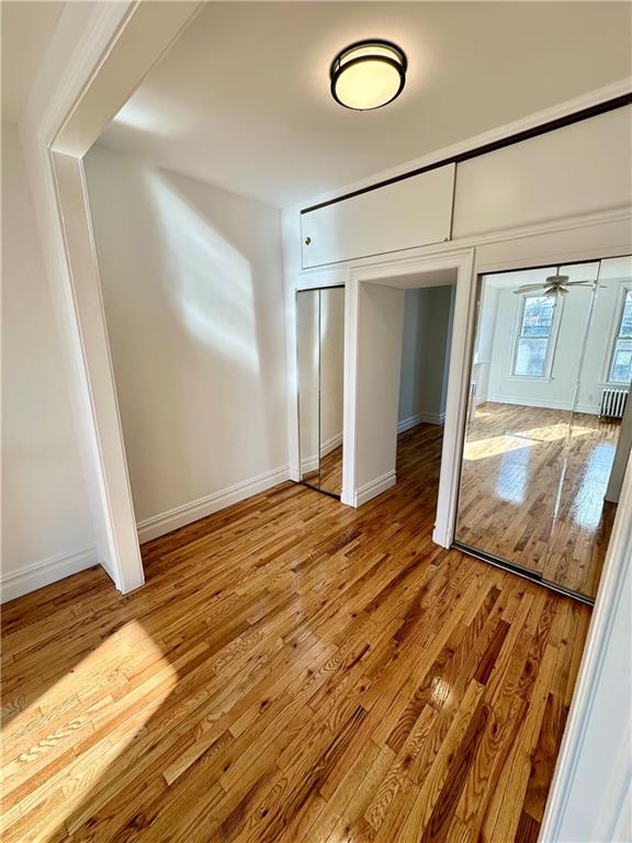 unfurnished bedroom with light wood-type flooring, baseboards, and two closets