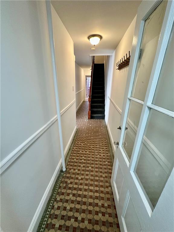 hallway with stairway, baseboards, and tile patterned floors