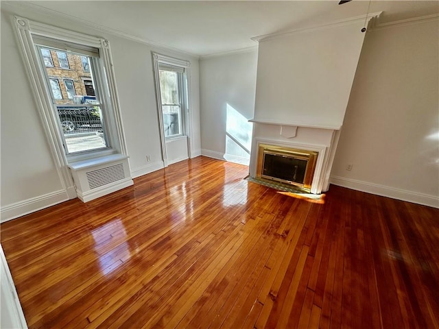 unfurnished living room featuring a fireplace with flush hearth, crown molding, baseboards, and hardwood / wood-style flooring