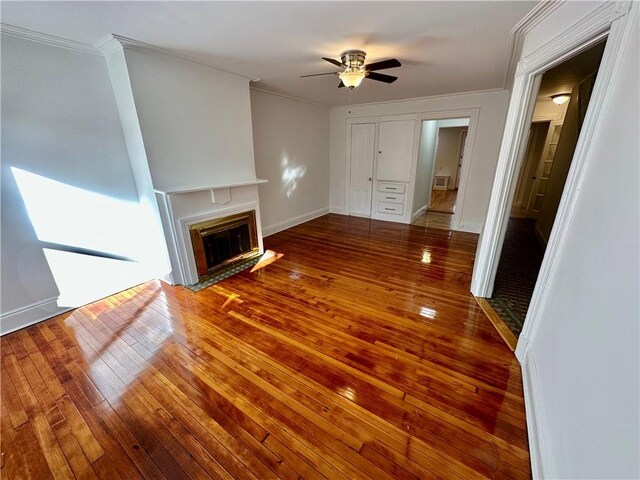 unfurnished living room featuring ceiling fan, wood-type flooring, and ornamental molding