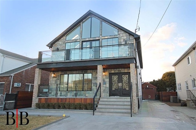 view of front of house with cooling unit, stone siding, a balcony, and covered porch