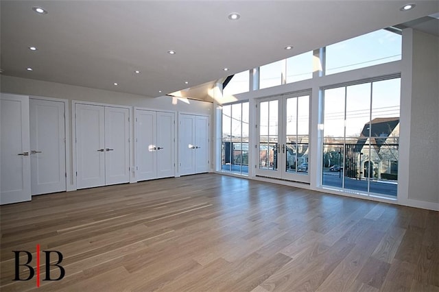 interior space featuring light wood-style floors, recessed lighting, and a towering ceiling