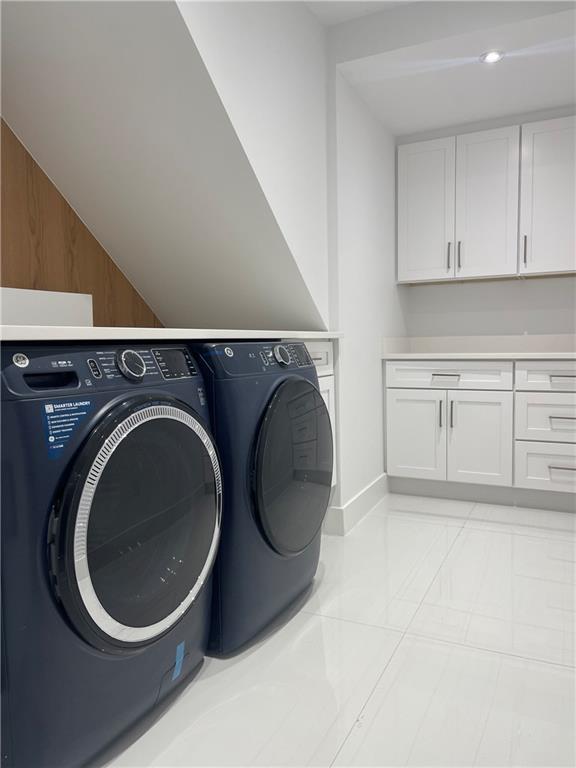 laundry area featuring cabinet space, light tile patterned floors, and separate washer and dryer