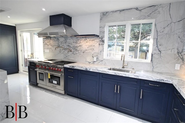 kitchen featuring exhaust hood, a sink, range with two ovens, backsplash, and blue cabinets