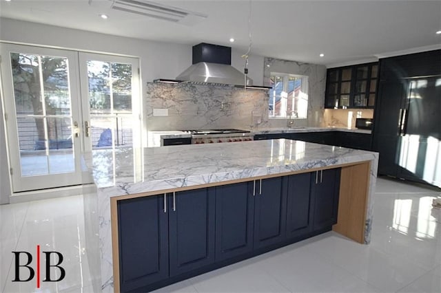 kitchen with decorative backsplash, wall chimney range hood, french doors, and a sink