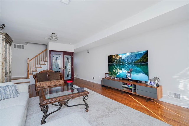 living room with visible vents, stairway, baseboards, and wood finished floors