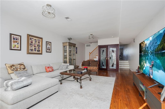 living area featuring visible vents, stairway, wood finished floors, and french doors