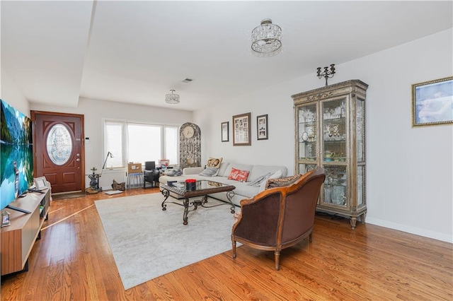 living room featuring visible vents, baseboards, and wood finished floors