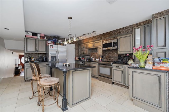 kitchen with light tile patterned floors, tasteful backsplash, dark countertops, appliances with stainless steel finishes, and a kitchen island