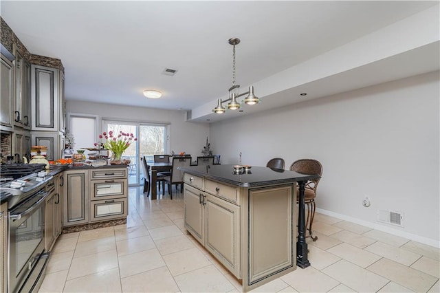 kitchen featuring dark countertops, visible vents, black gas range, and light tile patterned floors