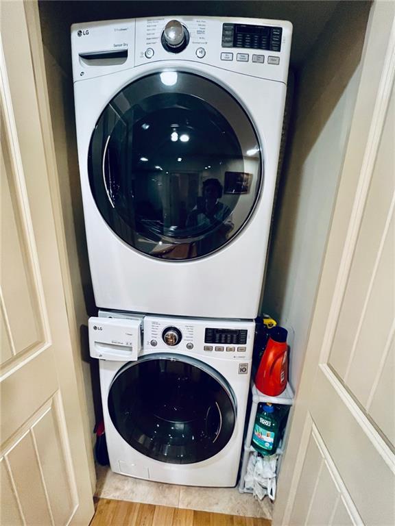 clothes washing area with light wood-type flooring and stacked washer / dryer