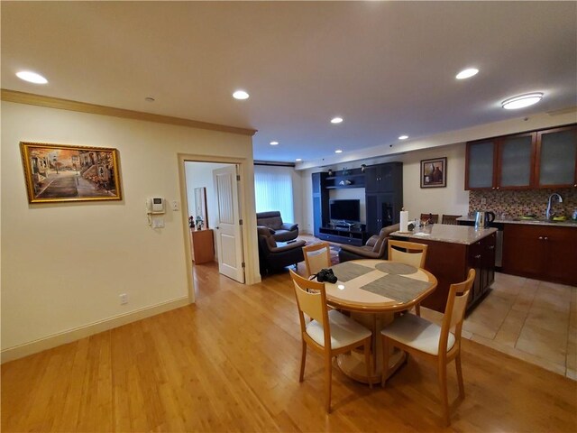 dining area featuring ornamental molding, light wood-type flooring, and sink