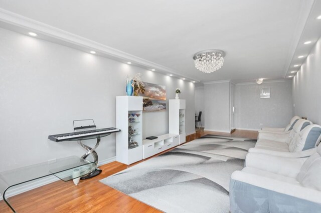 living room with a notable chandelier, crown molding, and wood-type flooring