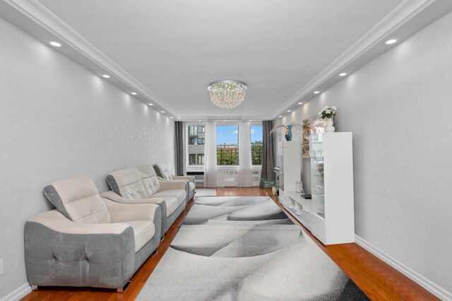 living room featuring crown molding, wood-type flooring, and a chandelier