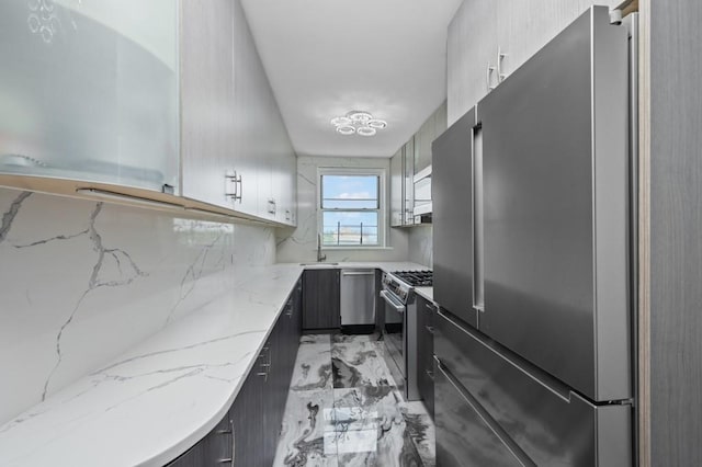 kitchen featuring stainless steel appliances, light stone countertops, and sink