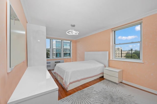 bedroom featuring radiator heating unit, crown molding, and wood-type flooring