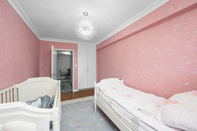 bedroom with crown molding, carpet floors, and an inviting chandelier