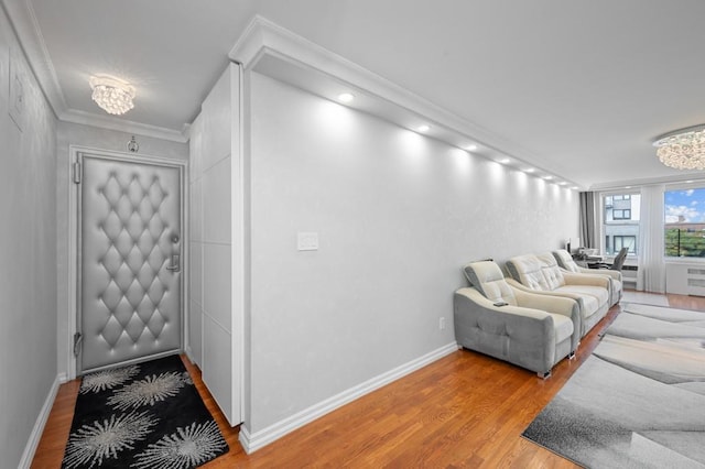 living area featuring an inviting chandelier, crown molding, light wood-style flooring, and baseboards