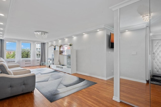 living room with ornamental molding, wood-type flooring, and a chandelier