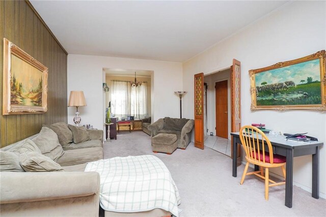 living room featuring light carpet, an inviting chandelier, and wooden walls