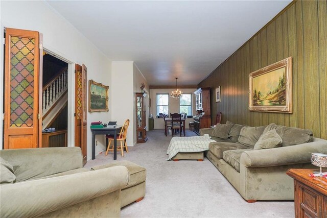 living room with light colored carpet, an inviting chandelier, and wood walls