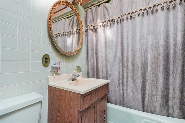 full bathroom featuring vanity, shower / bath combination with curtain, decorative backsplash, tile walls, and toilet