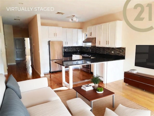 kitchen featuring gas stove, white cabinetry, light hardwood / wood-style floors, and stainless steel fridge