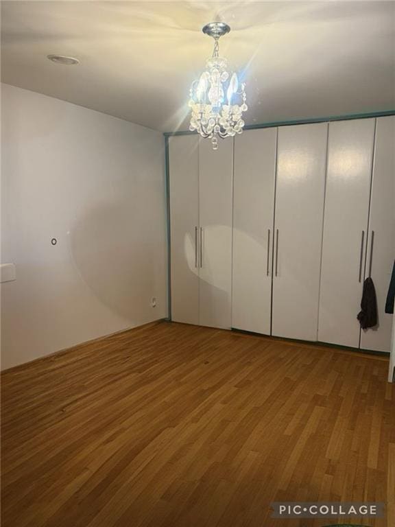 unfurnished bedroom with a notable chandelier and wood finished floors