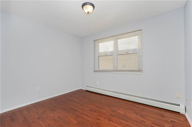 spare room featuring a baseboard radiator, baseboards, and wood finished floors