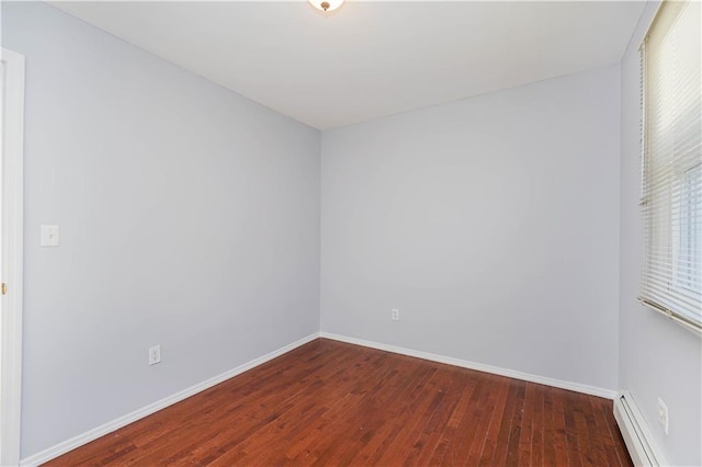 unfurnished room with baseboard heating, wood finished floors, and baseboards