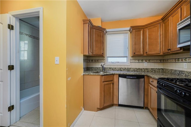 kitchen featuring light tile patterned flooring, stainless steel appliances, a sink, decorative backsplash, and brown cabinets