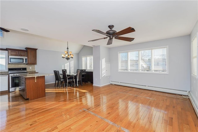 kitchen with lofted ceiling, appliances with stainless steel finishes, a baseboard heating unit, light wood-style floors, and a kitchen island