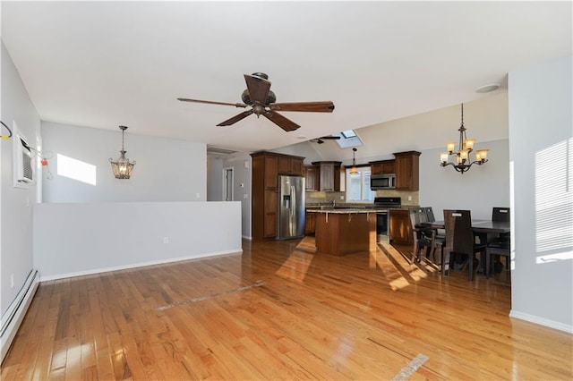 kitchen featuring a baseboard radiator, a kitchen island, appliances with stainless steel finishes, open floor plan, and light wood-style floors