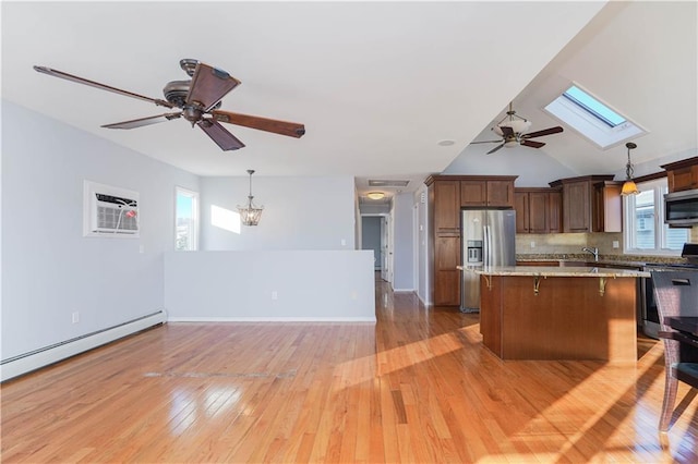 kitchen with appliances with stainless steel finishes, a breakfast bar area, a center island, light wood-type flooring, and a baseboard heating unit